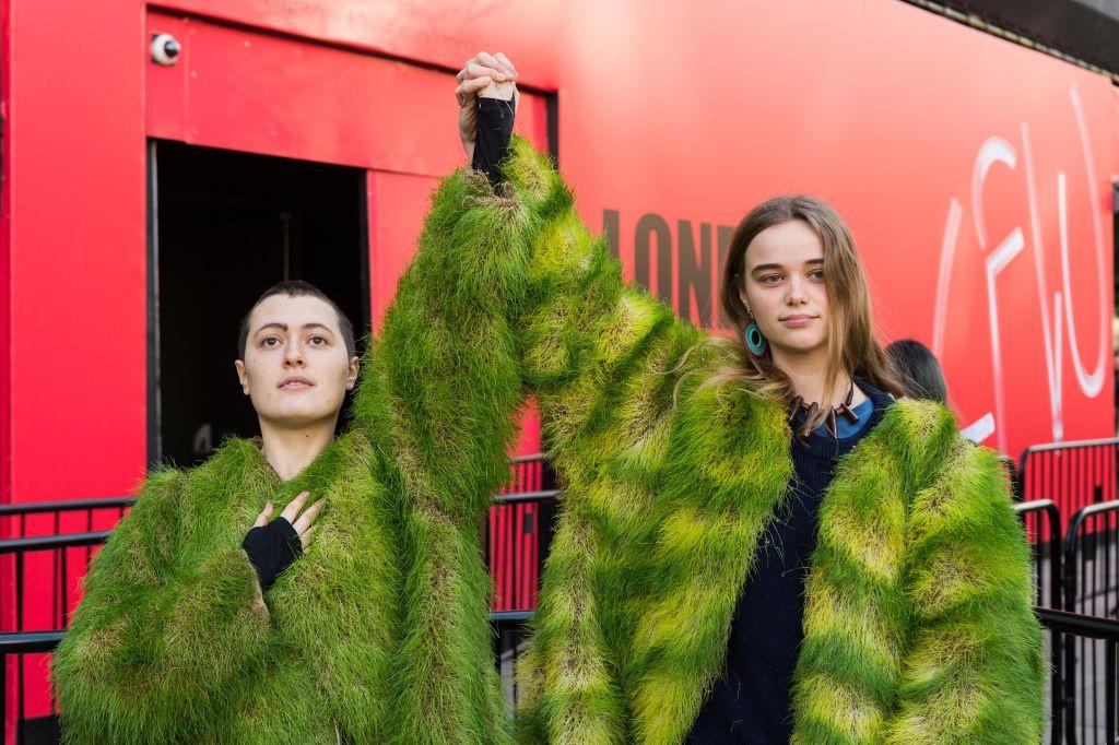 Activisten van de protestbeweging Extinction Rebellion dragen een jas uit gras om de impact van de mode-industrie op het milieu aan te klagen.