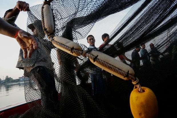 Vissers in de haven van Samut Sakhon controleren hun net nadat ze de vangst hebben binnengehaald. 