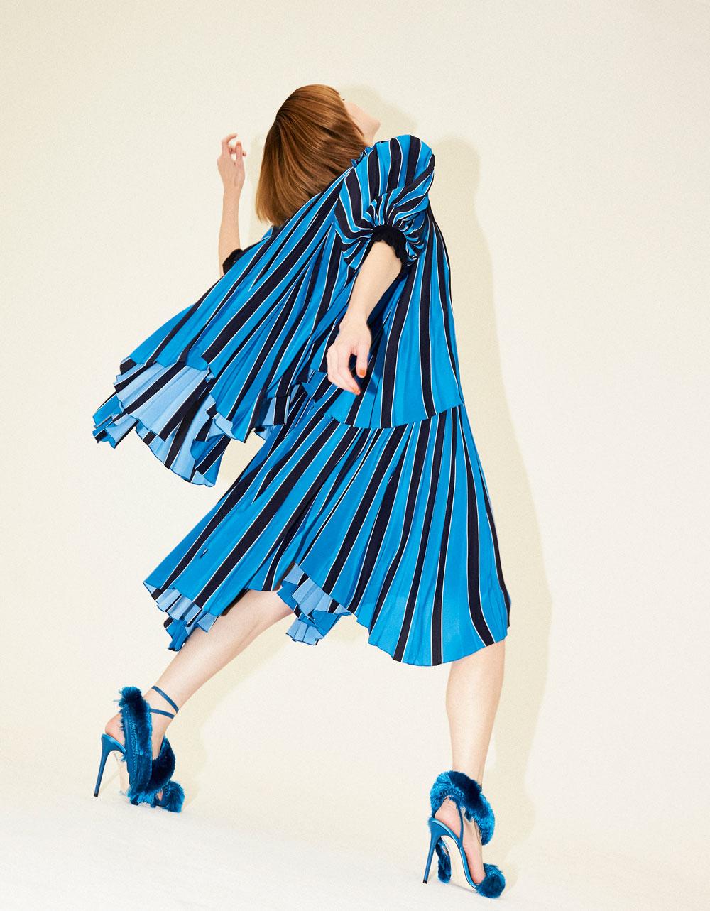 Blauwe, gestreepte plisséjurk met pofmouwen,  Givenchy. Blauwe satijnen sandalen met zijden franjes, Marco de Vincenzo.