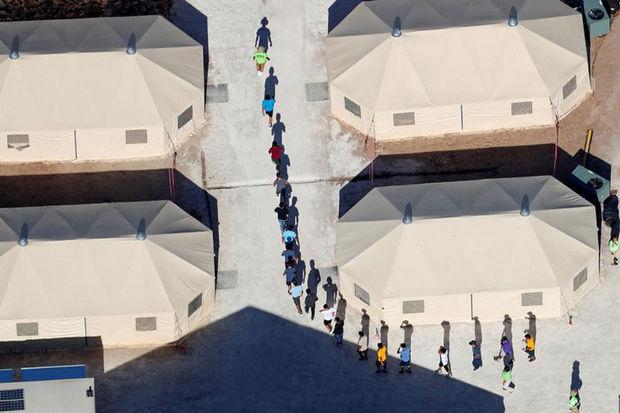 Een groep kinderen van migranten, van wie de meeste gescheiden werden van hun ouders, wandelen tussen de tenten in een opvangkamp aan de grens tussen de VS en Mexico.