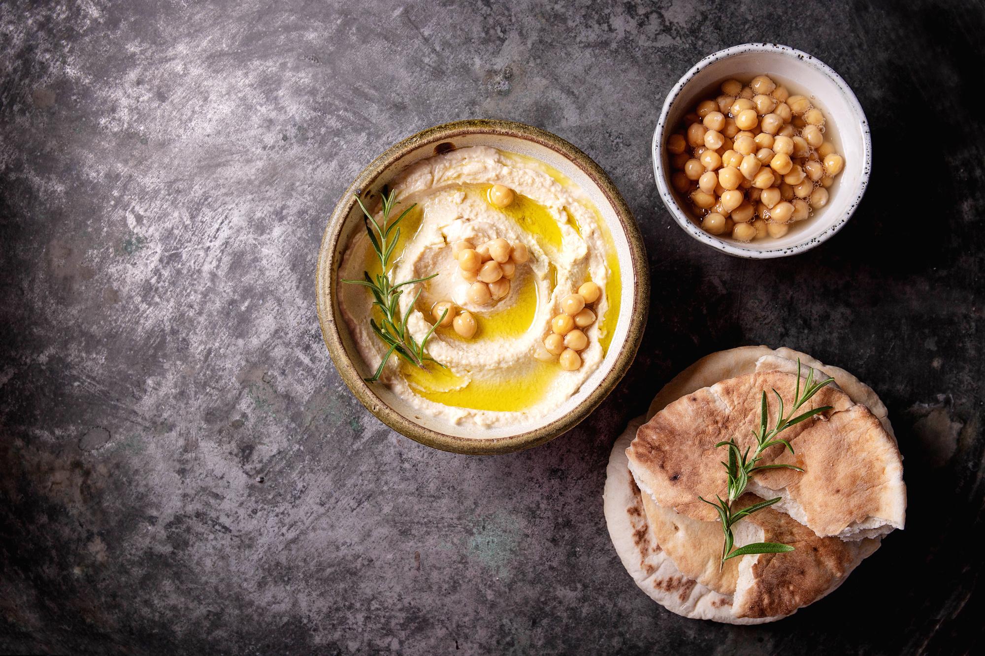Hummus serveer je lekker met verse kruiden en krokant brood.