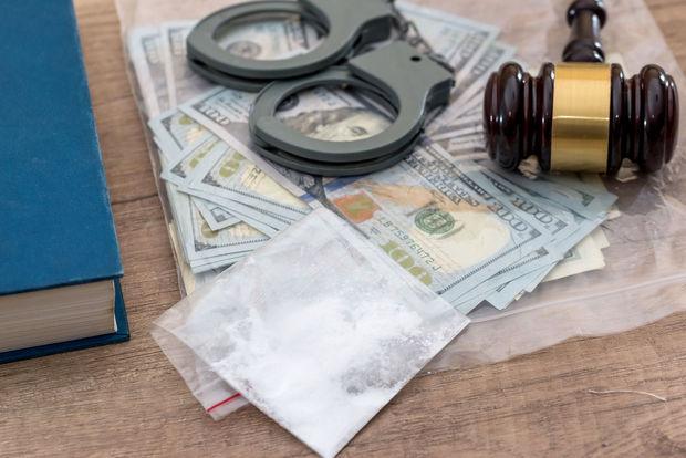 Drogues et substances illicites, dollars, livre, marteau de la justice et menottes