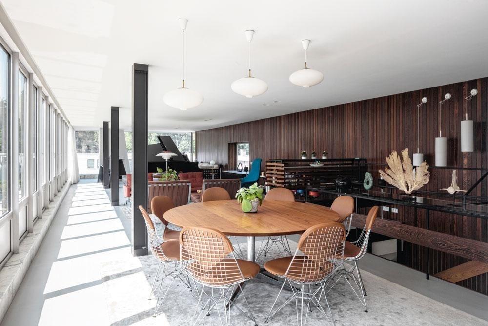 De trap leidt naar de open leefruimte met vooraan de eethoek. De tafel met houten blad komt uit de collectie van Knoll, de Wire Chairs van Eames zijn van Vitra.