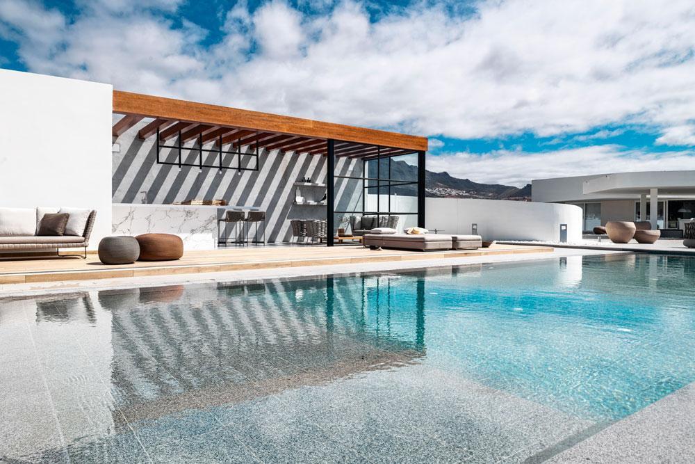Het losstaande poolhouse - met toog in keramisch marmer, stalen lichtstel en open dak - is een ontwerp van de Belgische interieurontwerpster Margot Pauwels.