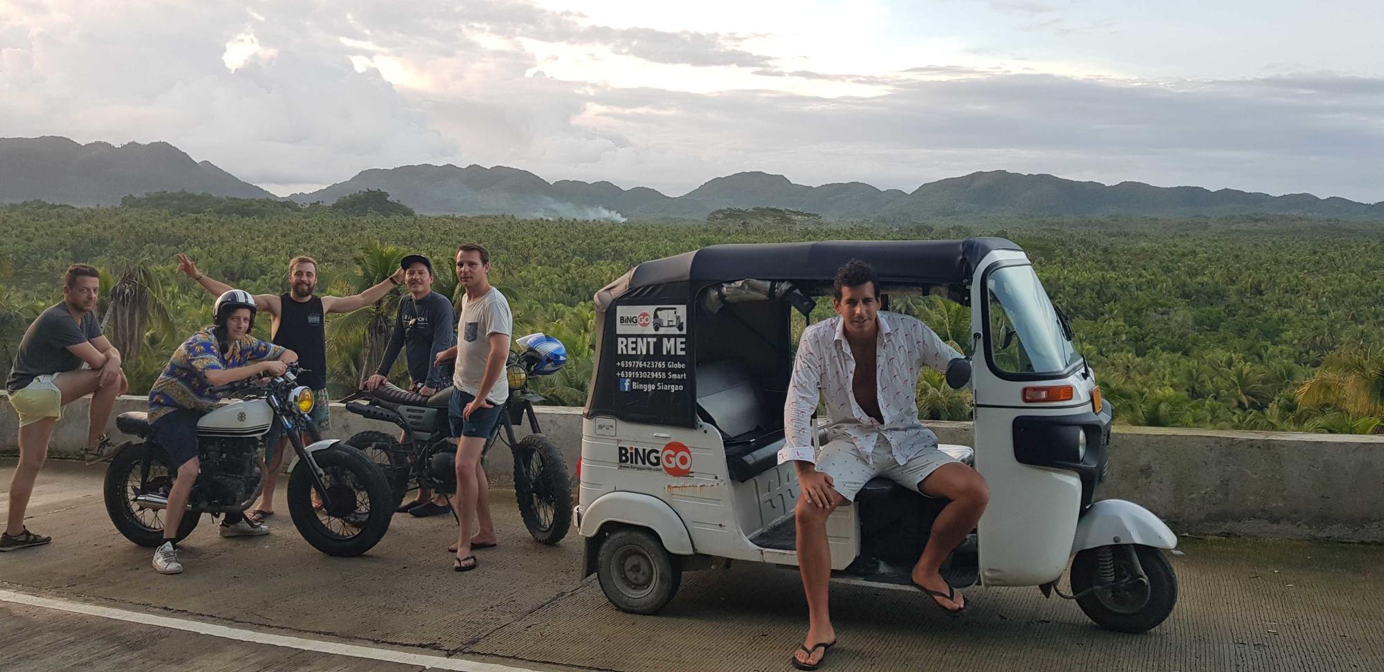 Een recente prospectie voor een nieuwe tuktuk-trip. Charles leunt op de tuktuk, Simon zit op de moto.