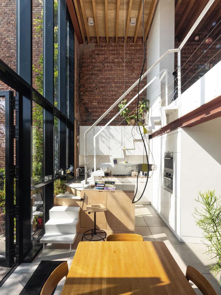 De compacte keuken met schuine trap die over het aanrecht loopt is een ontwerp van Komaan Architecten.