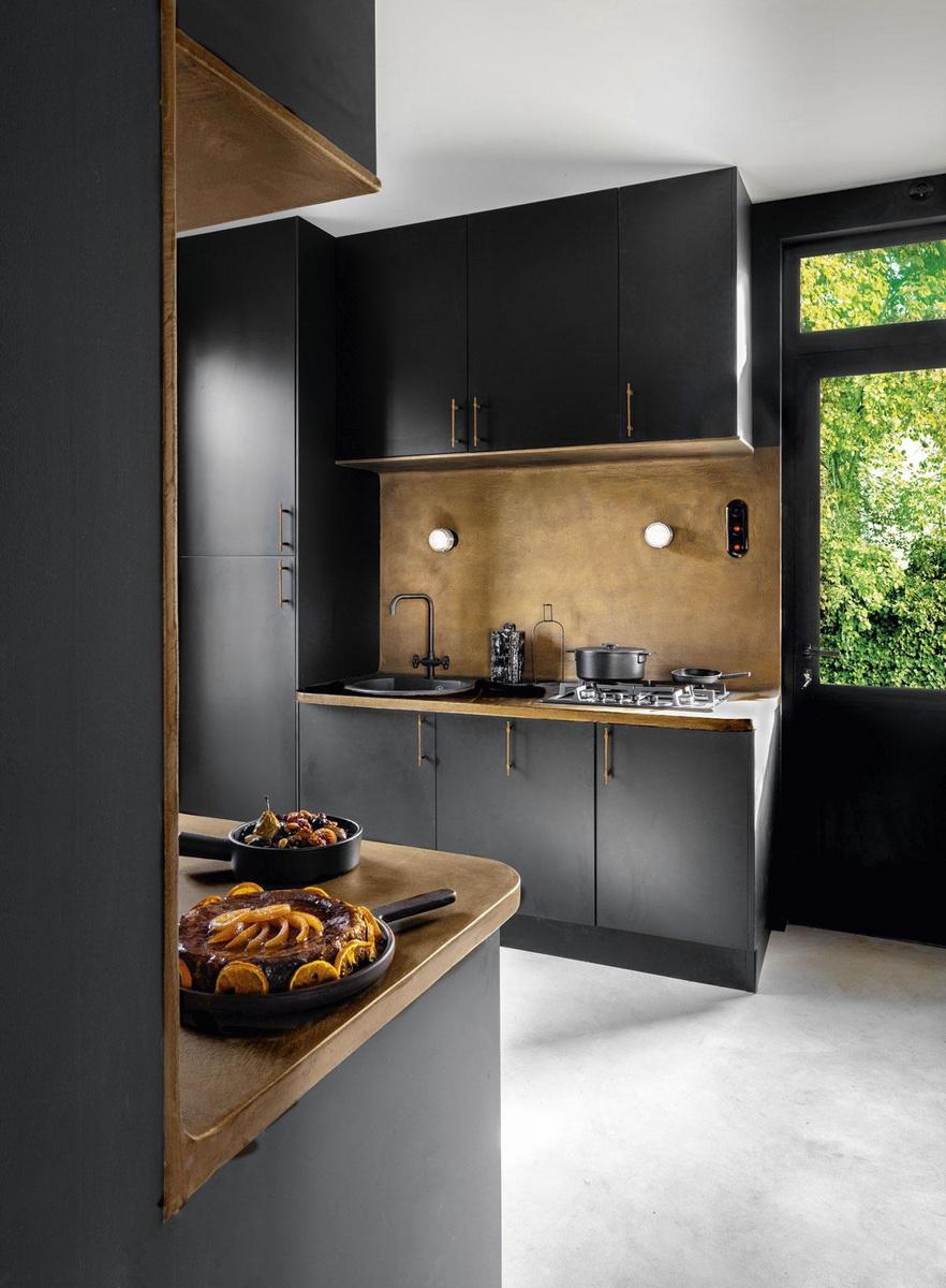 De zwarte keuken van Oskab heeft bronskleurige handvatten van het Belgische merk Dauby.