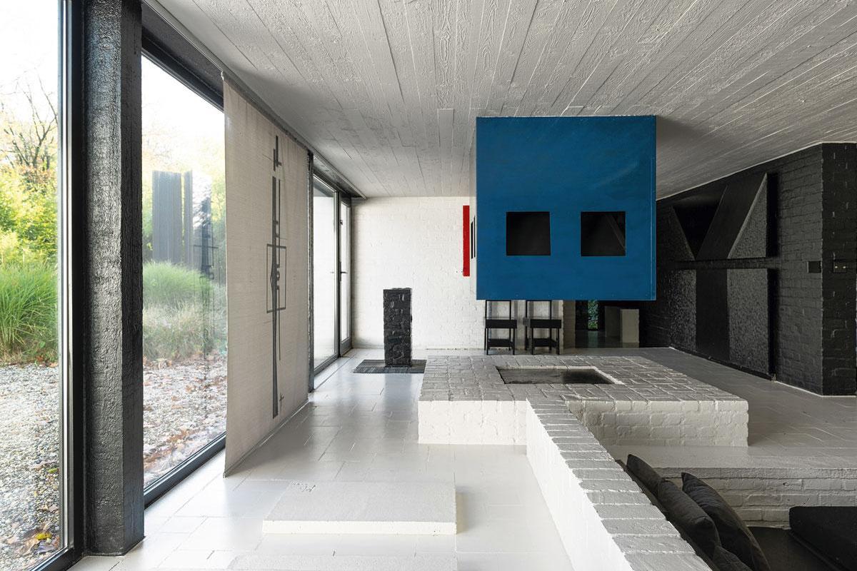 Rechts is een zitkuil, links de ingang van het huis, met in de voortuin twee betonnen sculpturen.