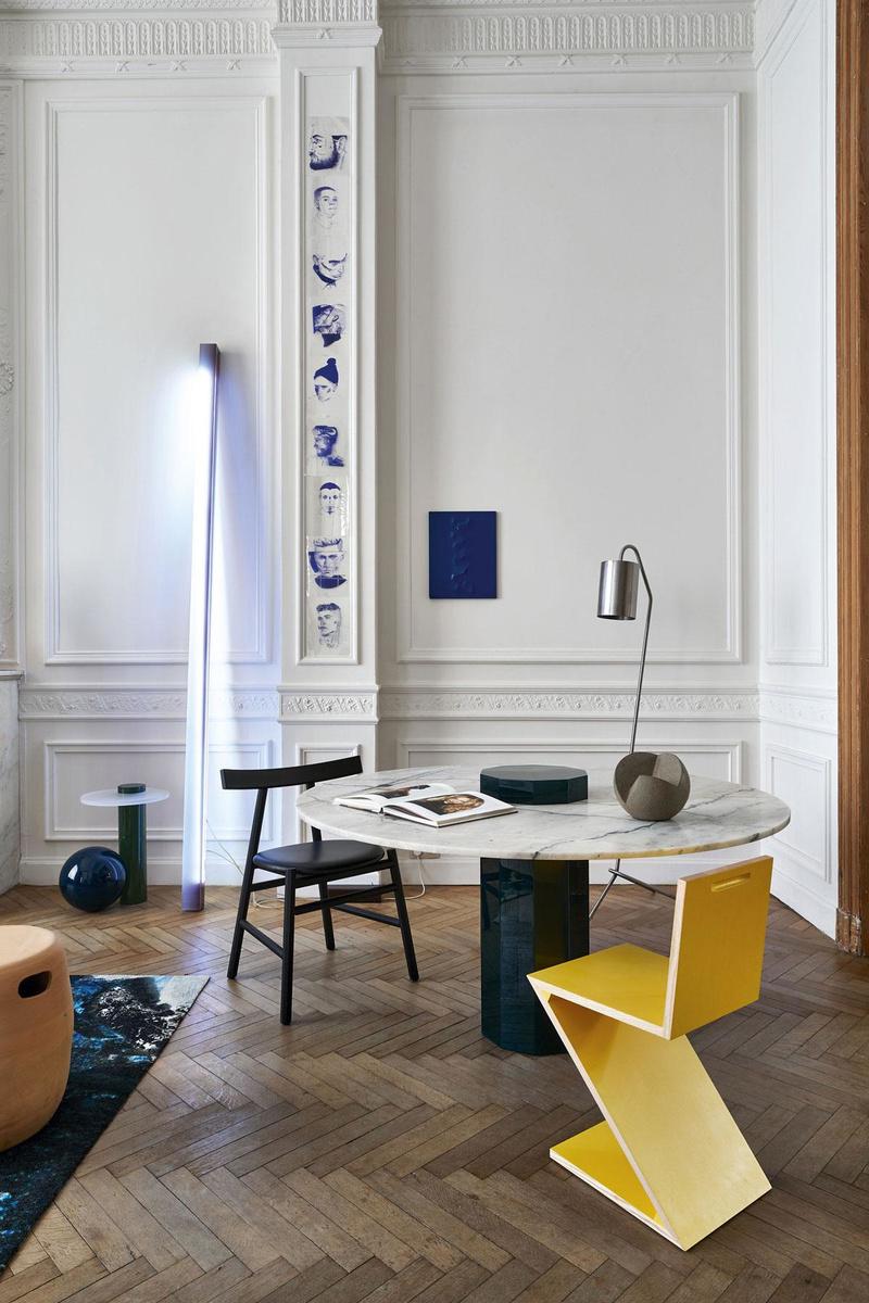 Rond de nog naamloze eettafel van marmer en resine staan een zigzagstoel van Gerrit Rietveld en een stoel van La Chance in Parijs. De pentekeningen zijn van de Antwerpse illustrator Nicolas Colaert, met wie Hugues heeft samengewerkt voor Essentiel. Het blauwe Deforming is een kunstwerk van de Italiaan Luchipe, de metalen lamp een prototype voor 'Otho' uit de Solids-collectie.