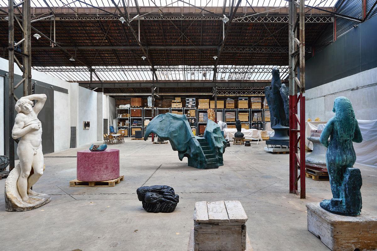 Het atelier van Johan Creten, in een oude fabriek in de Parijse voorstad Montreuil, met links De Stervende Slaaf van Michelangelo, in gips, en Cretens eigen werk, waaronder Les Amants (vooraan), De Vleermuis (midden, 2014-19), Pliny's Sorrow (achteraan, 2011-2014) en The Herring (rechts, 2018).