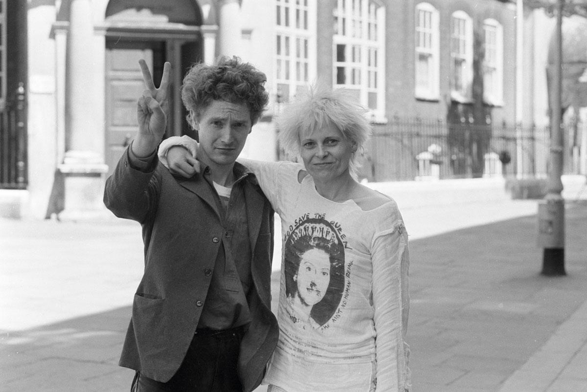 McLaren en Westwood voor Bow Street Magistrates' Court, na een arrestatie in 1977. Westwood draagt een klassiek punk-T-shirt, met een afbeelding van de Queen met een veiligheidsspeld door de neus.