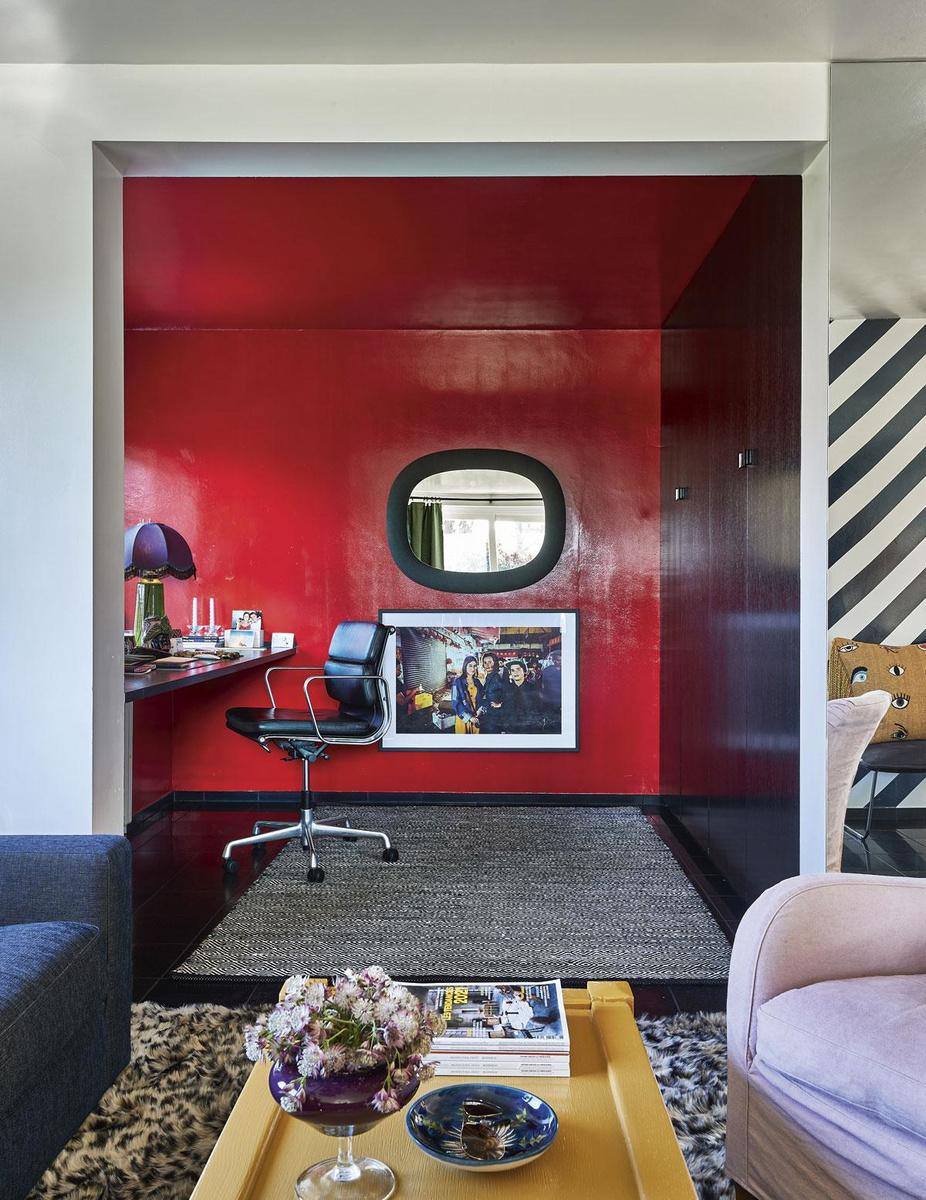 Heel hun woning is een intuïtieve kleurbom vol onverwachte hoekjes, zoals dit knalrode bureau. Glansverf is de enige rode draad in het interieur.