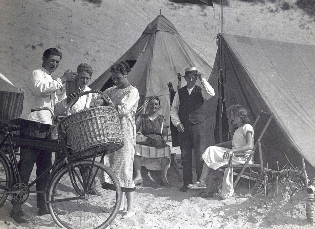 Bakkersjongen bezorgt brood aan badgasten die op het strand kamperen, Nederland (1923).