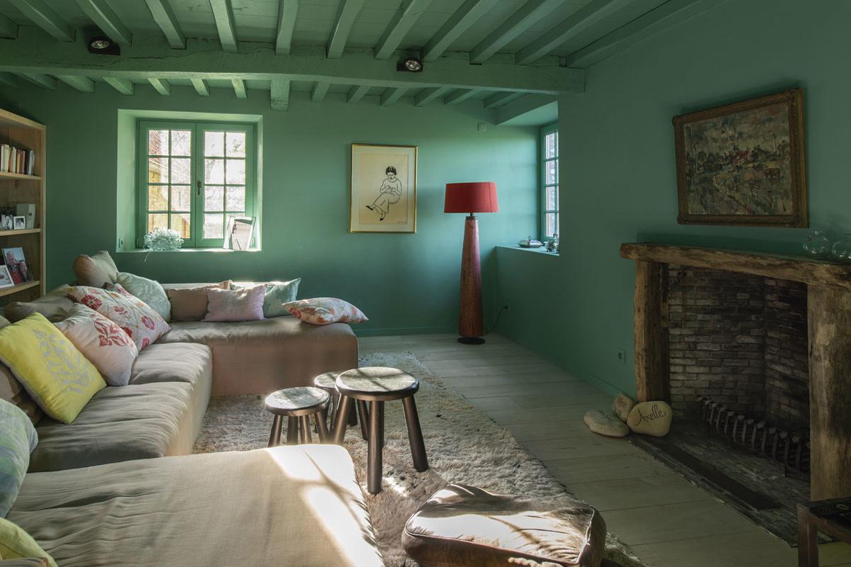 De pastelroze sofa van Munt in Brugge valt op in de smaragdgroene tweede woonkamer. De kleur Arsenic van Farrow & Ball is een knipoog naar Isabels beroep als arts. Aan de muur hangt een werk van Gustaaf De Smet. De salontafels behoorden tot een PS-collectie van Ikea, op de vloer ligt een authentiek Beni Ouarain-berbertapijt.