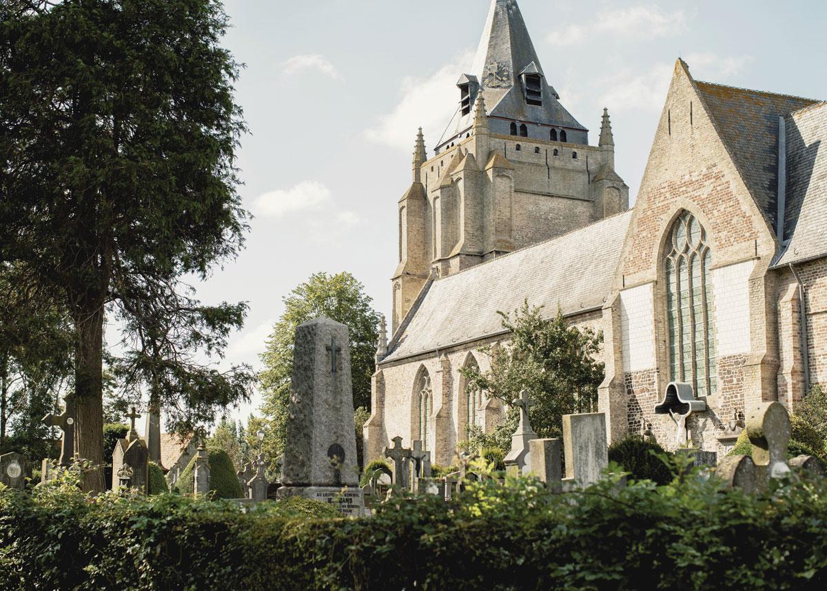 De imposante Onze-Lieve-Vrouw- Hemelvaartkerk van Houtem. Aan de overkant ligt een kleine pastorie, waar koning Albert I vaak verbleef tijdens de Groote Oorlog.