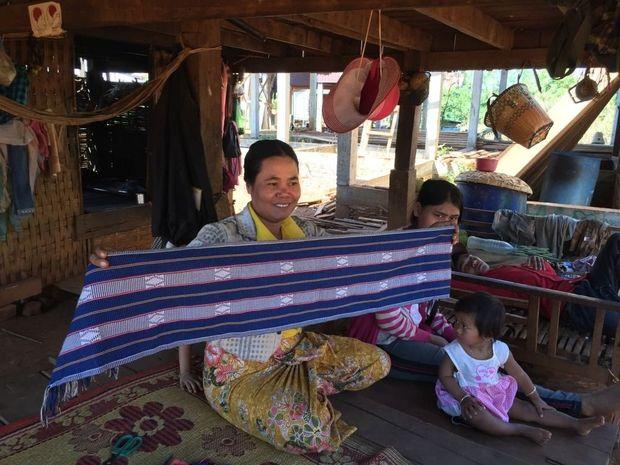 Een vrouw in Phnom Village weeft traditionele sjaals.