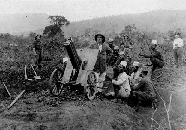 Officier européen et soldats congolais près d'une pièce d'artillerie, lors de l'offensive en Afrique orientale allemande.