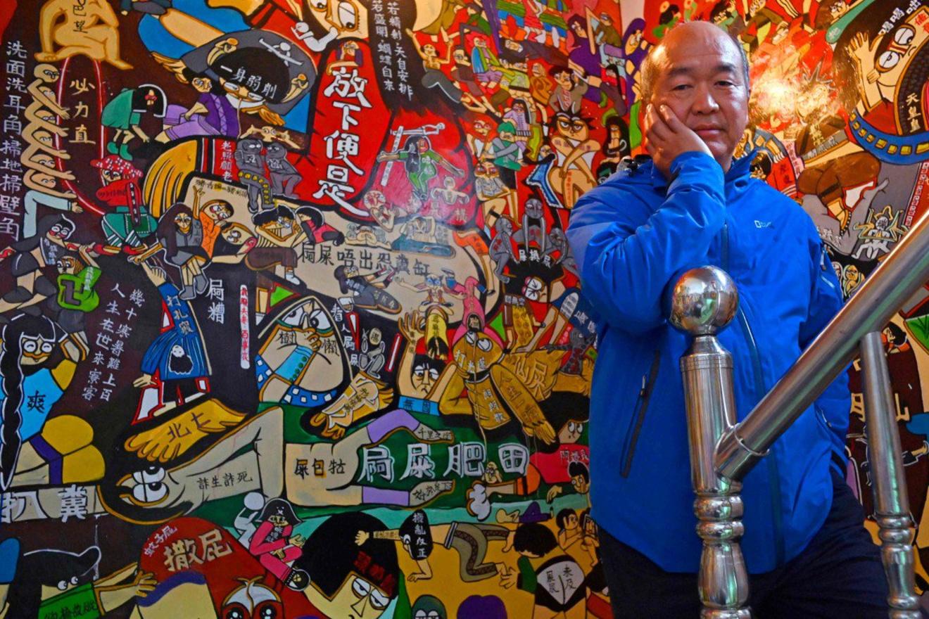 Taiwanese graffiti-artiest Wu Tsun-hsien poseert voor een versierde muur