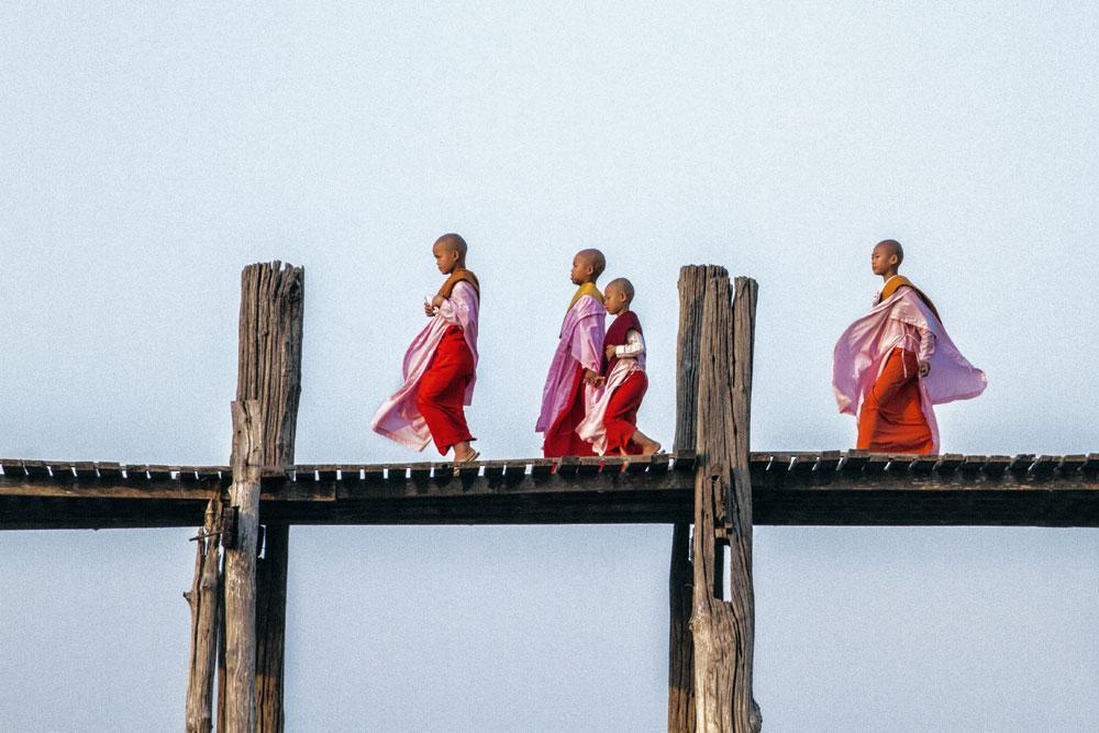Dans la ville sainte bouddhiste de Mandalay, en Birmanie, de jeunes novices arpentent le pont U Bein posé sur un lac à la sortie sud de la ville. Entièrement construit en teck il y a près de 200 ans, il déploie son 1,2 km sur de frêles pilotis érodés par le temps.