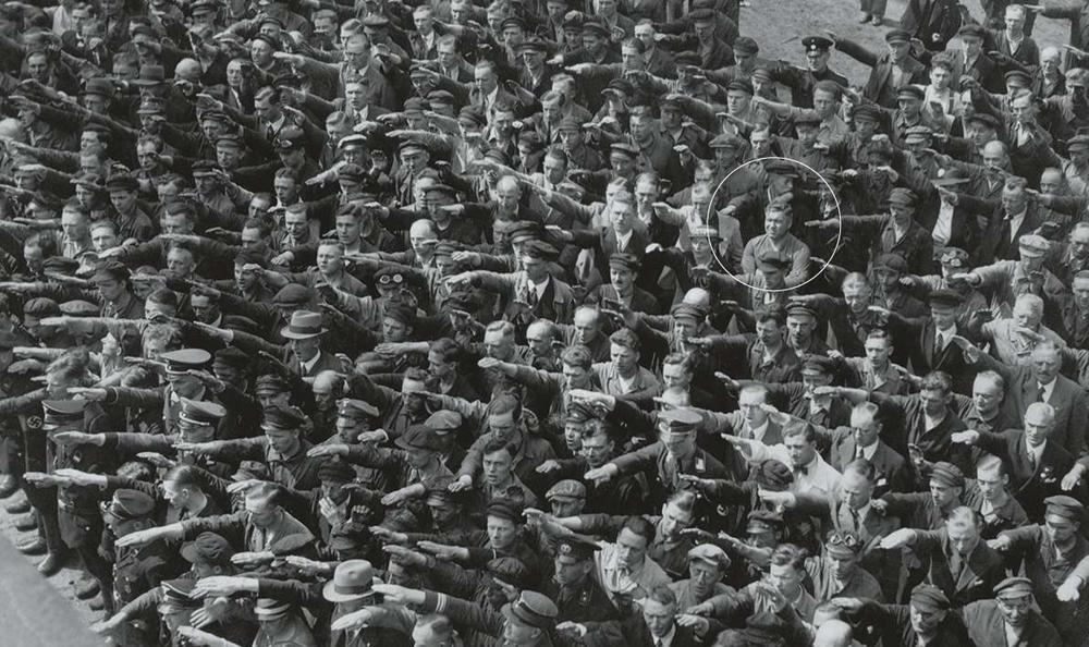 Célèbre photo prise au chantier naval de Hambourg (1936), montrant August Landmesser (en haut à droite), un ouvrier allemand, croisant les bras, seul à ne pas faire le salut hitlérien.
