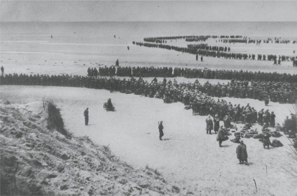 De longues files de militaires sur la plage de Dunkerque attendent que l'on vienne les chercher.