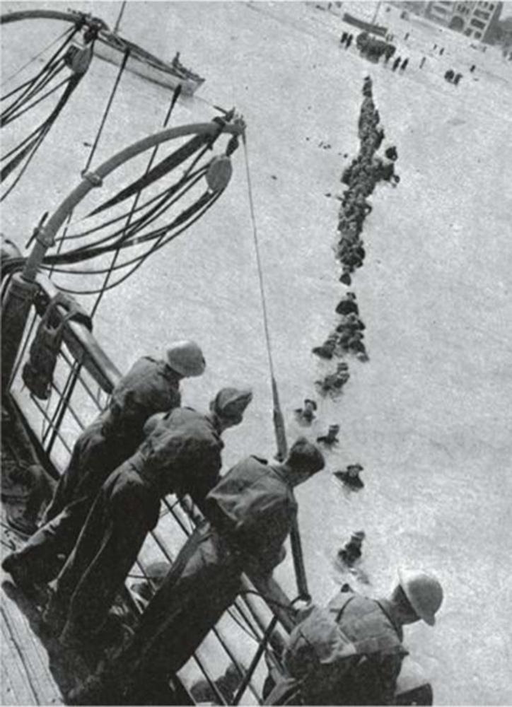 Les soldats marchent dans l'eau peu profonde pour monter à bord d'un bateau.