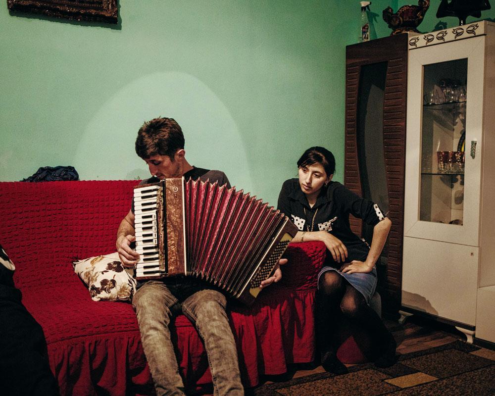 Ziyal Béridzé, jeune habitant de Ghorjomi, joue de l'accordéon dans le salon de sa nouvelle maison.