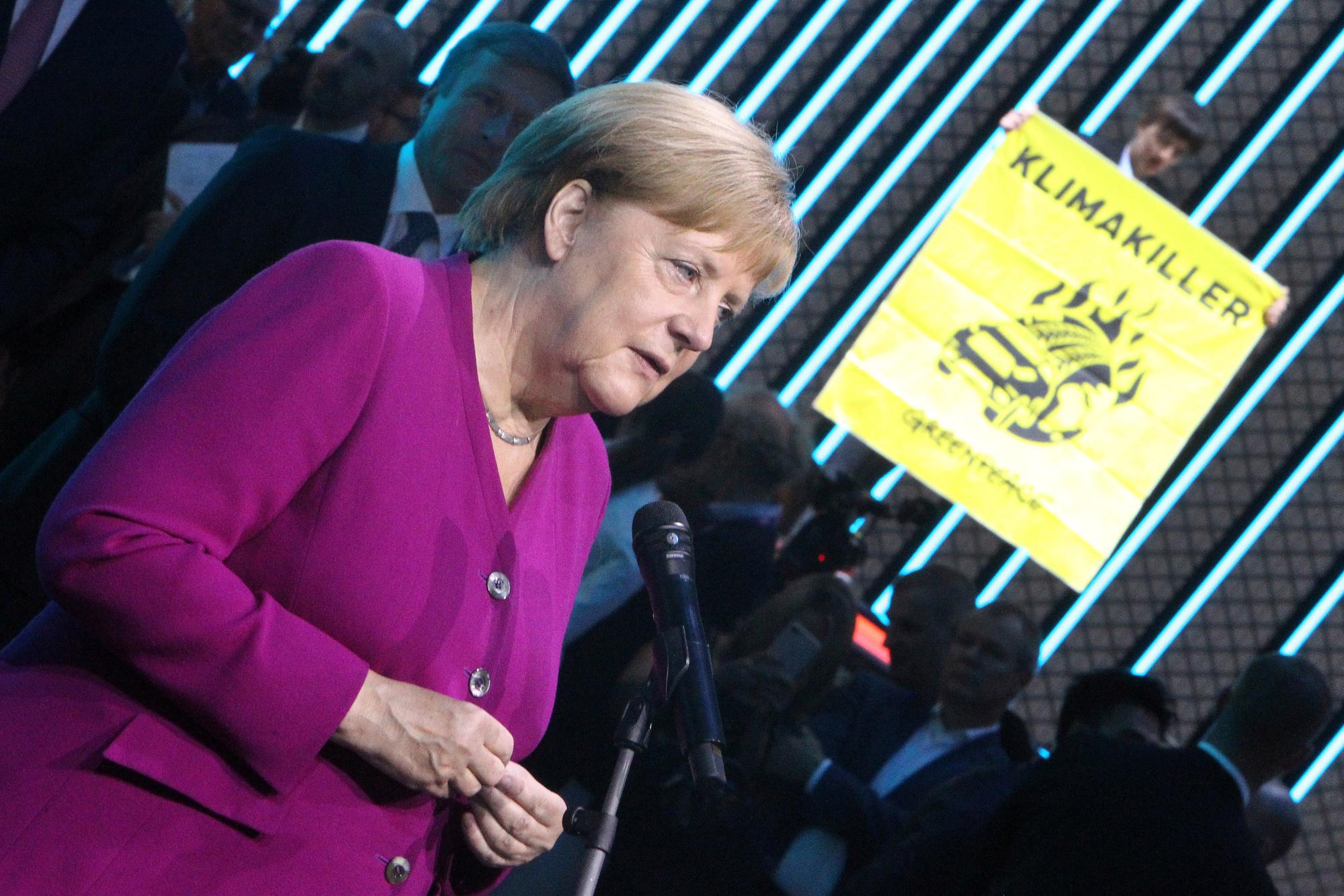 Un activist de Greenpeace monte avec son affiche sur le toit d'une voiture pendant la visite d'Angela Merkel