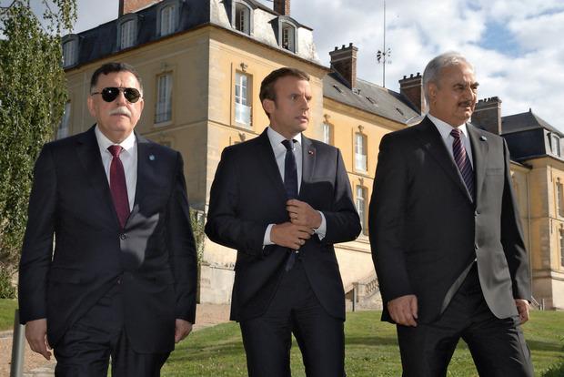 Le président français Emmanuel Macron entouré des deux rivaux pour la conclusion d'un cessez-le-feu : Fayaz al-Sarraj (à g.) et Khalifa Haftar, le 25 juillet, à La Celle-Saint-Cloud près de Paris.
