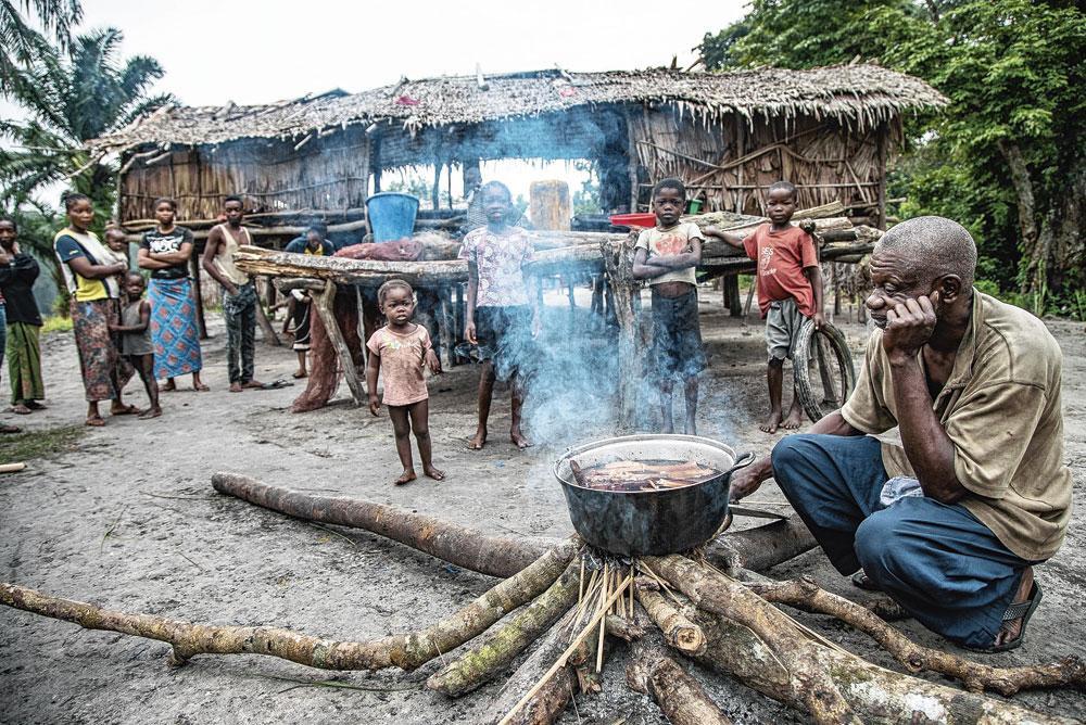 Au camp de pêche de Mpeka installé sur la rivière Ruki, le chef du village fait bouillir l'écorce d'arbres  de la forêt qu'il utilisera comme remède traditionnel.