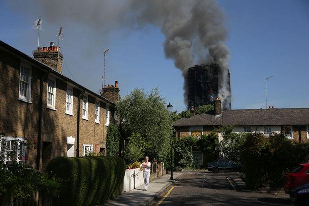 Local residents watch smoke billow from Grenfell Tower, a residential block on June 14, 2017 in west London. The massive fire ripped through the 27-storey apartment block in west London in the early hours of Wednesday, trapping residents inside as 200 firefighters battled the blaze. Police and fire services attempted to evacuate the concrete block and said 
