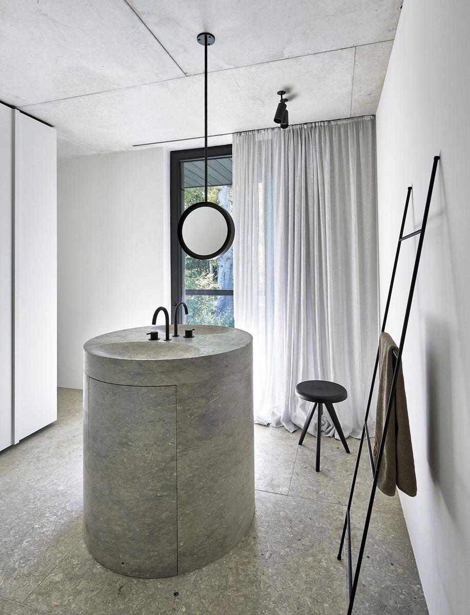 L'architecte Hans Verstuyft a conçu un lavabo rond en pierre naturelle, le seul élément démonstratif de cette salle de bains où tout le reste est caché derrière des armoires.