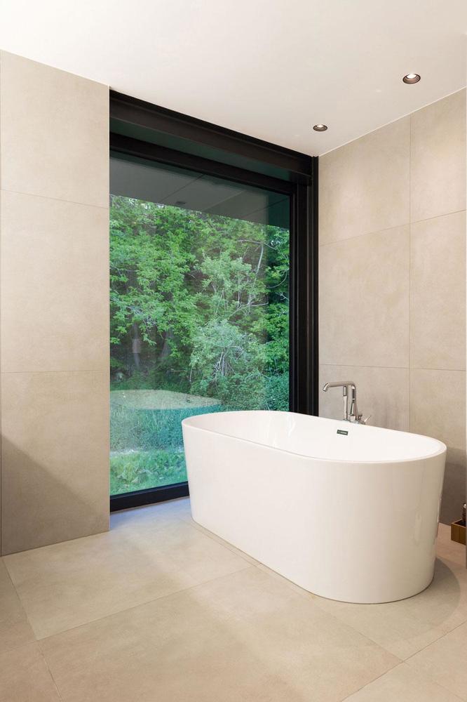 La salle d'eau offre un design très épuré, avec une baignoire donnant l'impression de prendre son bain en pleine nature.