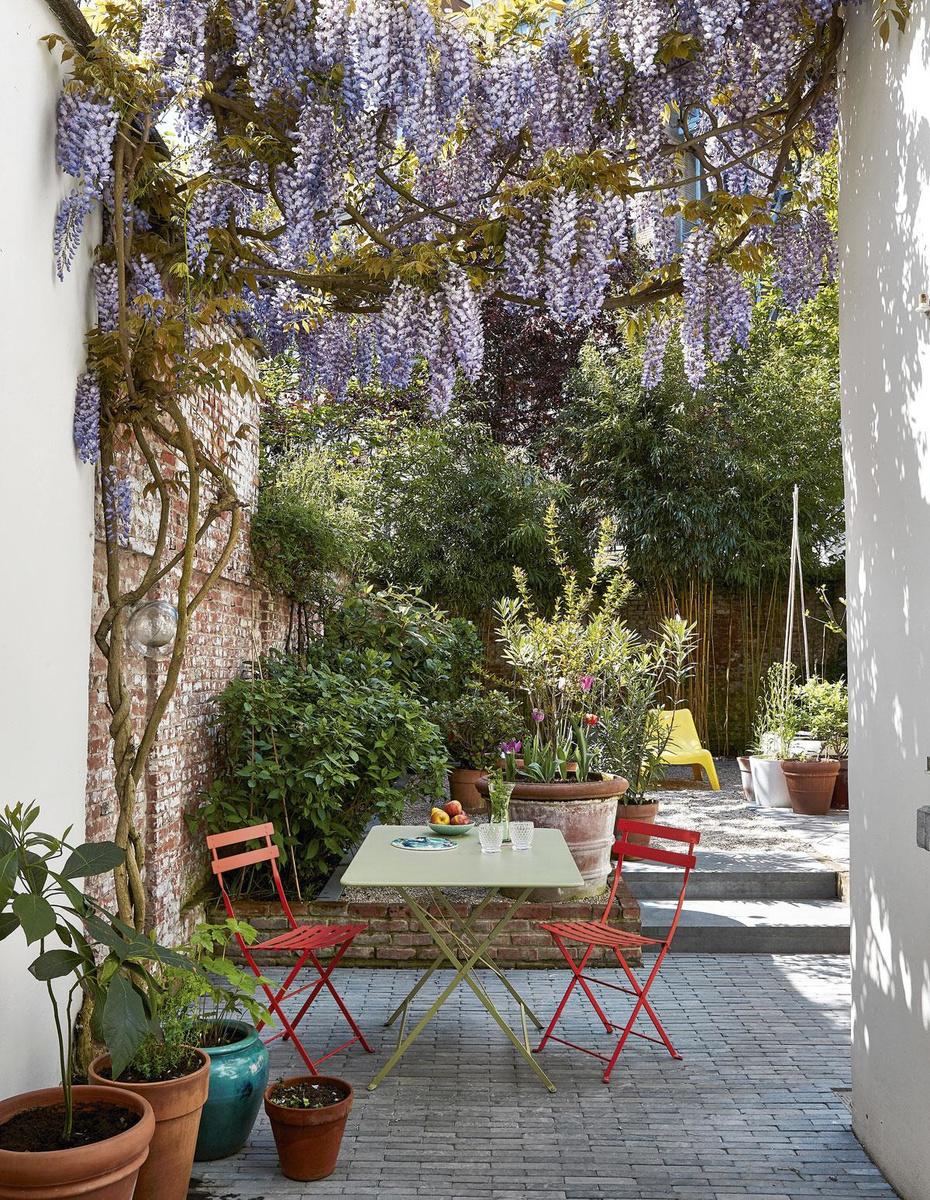 Les chaises bistro Fermob et la végétation dense donnent une ambiance provençale à ce jardin.
