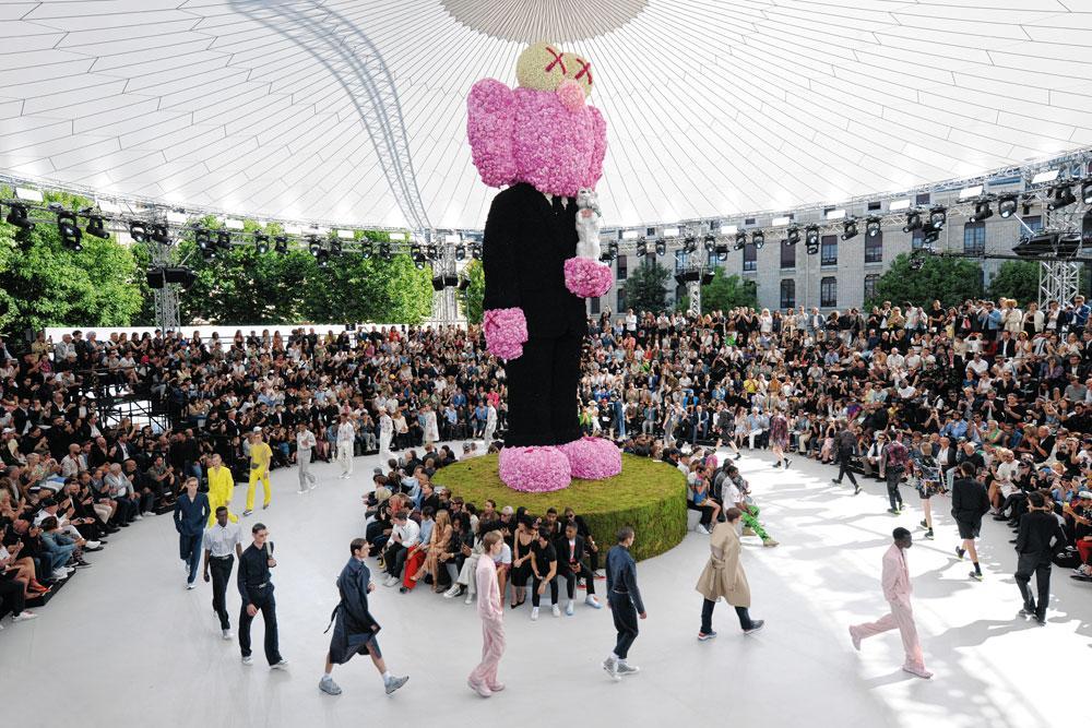 L'Homme Dior, désormais revu par Kim Jones et défilant autour d'une sculpture florale de Kaws.