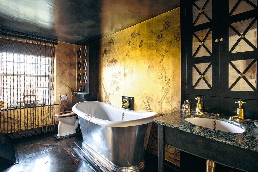 La salle de bains, dont les murs sont couverts de papier peint de feuille d'or imprimé à la main par la maison de Gournay.