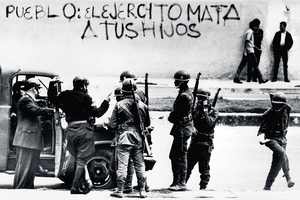 Des soldats montent la garde à Mexico City, face au mur orné d'un grafitti : 