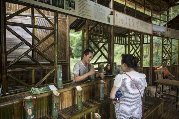 Un touriste achetant de l'alcool vieilli dans des bambous.