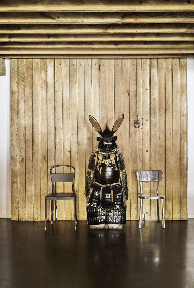 Devant un panneau de bois chiné rue Blaes à Bruxelles, une armure de samouraï provenant de la galerie Cécile Kerner se dresse entre une chaise A4 en alu recyclé éditée par EOQ et un modèle Déjà-Vu de Magis.