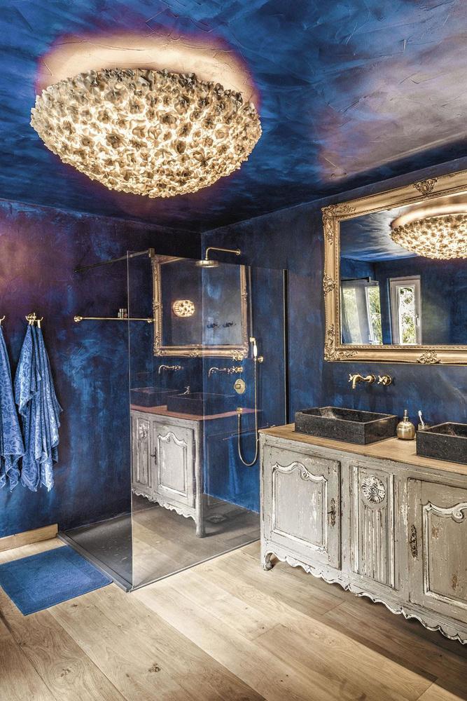 Dans la salle de bains aux murs nappés de Mortex teinté avec un pigment cobalt, les meubles sous vasques ont été fabriqués à partir d'un ancien buffet, détourné de sa fonction première.