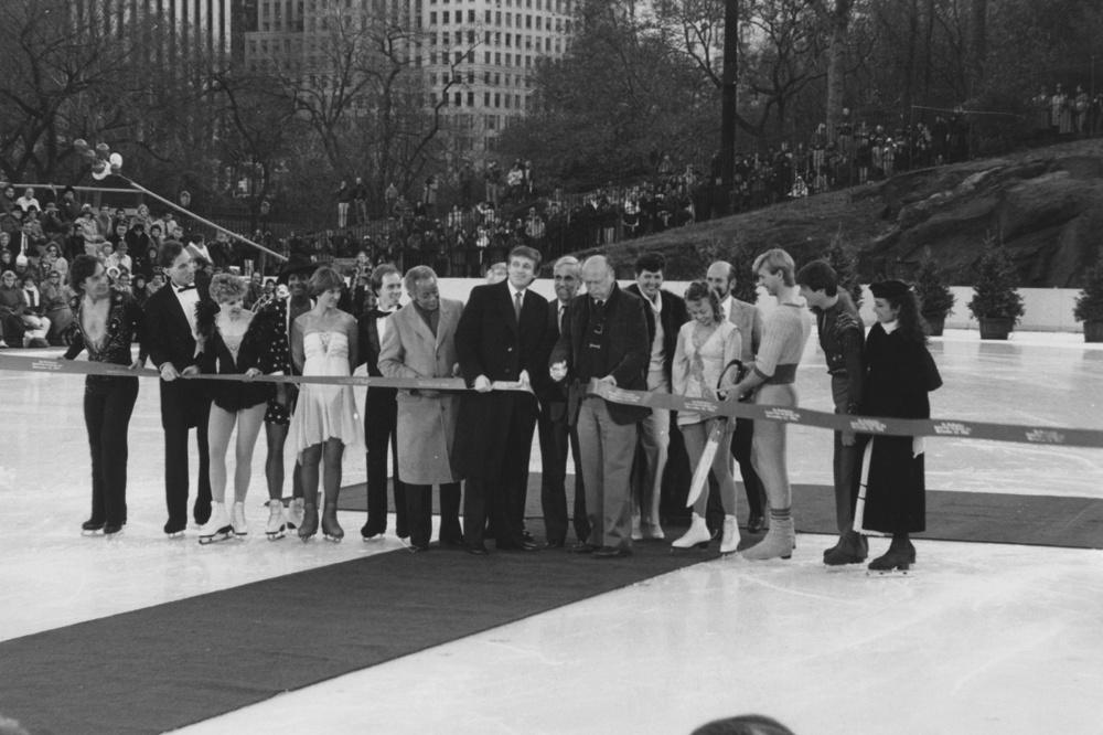 L'homme d'affaires américain Donald Trump (au centre, à gauche en long manteau foncé) lors de la cérémonie de réouverture de la patinoire Wollman à Central Park, New York, le 13 novembre 1986. Le maire de New York, Ed Koch (1924 - 2013), coupe le ruban.