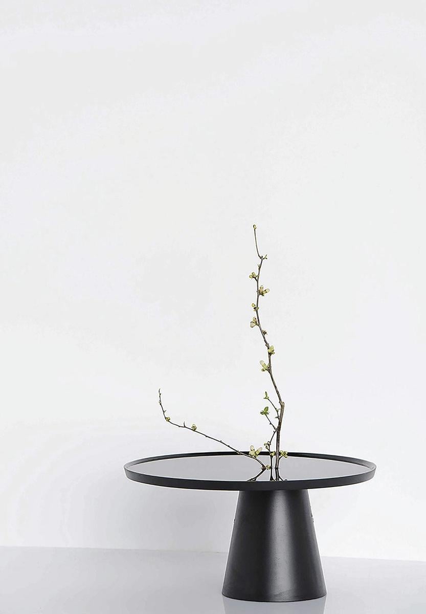 Cette table basse de Kenzo Tadaka, dotée d'un trou en son centre et d'un pied pouvant être rempli d'eau, est un hommage à l'art de l'ikebana.