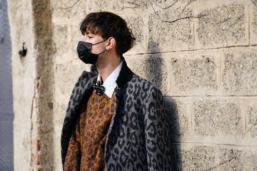 Un invité porte un masque noir, un manteau gris imprimé léopard, un pull brun en laine imprimé léopard, une chemise blanche, à l'extérieur de BOSS, pendant la Fashion Week de Milan automne/hiver 2020-2021
