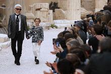 Karl Lagerfeld salue à la fin du défilé Croisière de Chanel, en compagnie de son fllleul Hudson Kroenig, le 3 mai 2017, à Paris