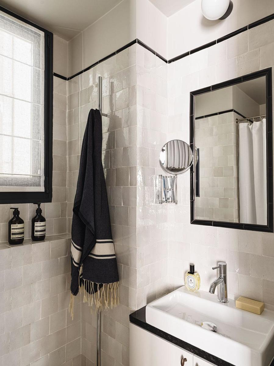 La salle de bains joue sur une palette graphique en noir et blanc, avec des zelliges comme revêtement mural.