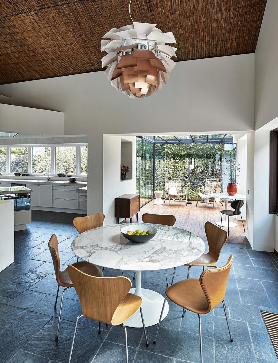 Tous les meubles ont été choisis en tenant compte de l'année de construction de la villa. Une suspension Artichoke de Louis Poulsen surplombe une table Tulipe d'Eero Saarinen et des chaises Papillon d'Arne Jacobsen.