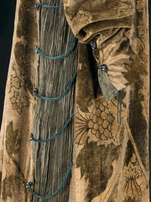 Robe Eleonora (détail, vers 1912), par Mariano Fortuny (1871-1949). Velours de soie vert imprimé or, taffetas de soie vert plissé, cordonnet de soie vert, perles en pâte de verre noir et blanc. Doublure en taffetas de soie or. 