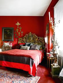 Dans la chambre, le fil... rouge est bien présent : au sol, sur les parois ou sur le lit de style baroque. Au mur, on aperçoit la collection de croix de Carlo et une peinture flamande datant du xviie siècle.