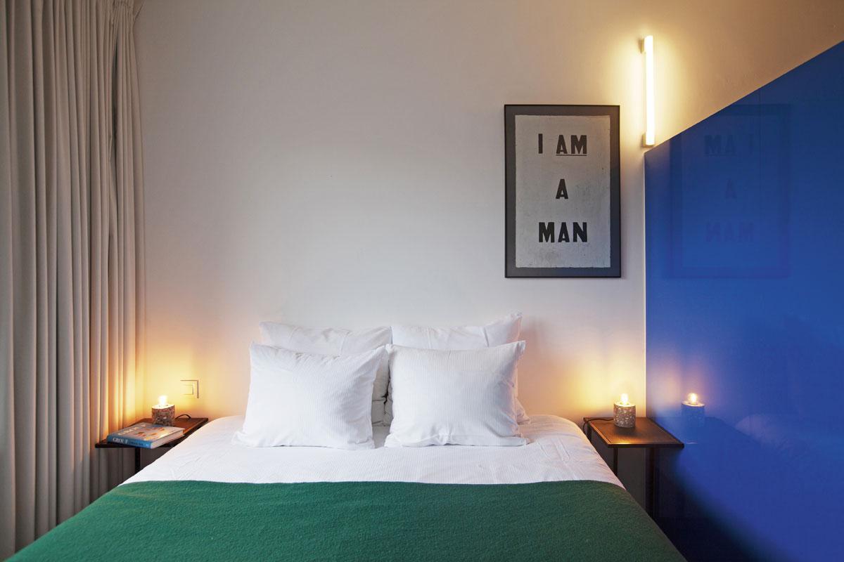 Cet appartement fait presque office de galerie d'art, avec des oeuvres de Glenn Ligon. Le couvre-lit vert provient de l'Hotel Pilar, à Anvers, dont Sam Peeters est le copropriétaire. Du textile fabriqué spécialement pour l'établissement est vendu en ligne. Le mur bleu vif est un clin d'oeil au travail de l'artiste Donald Judd.