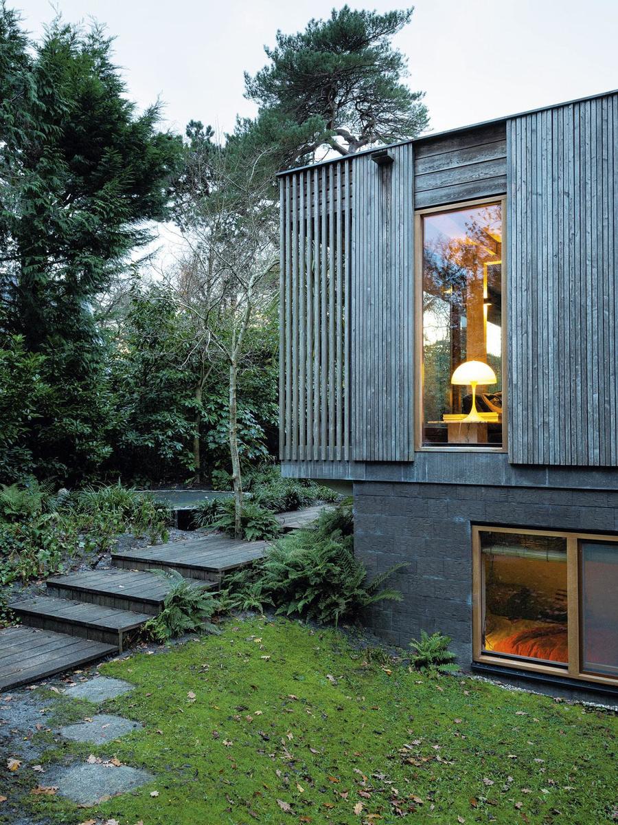 La façade de la maison mixe un bardage en pin thermo-traité et un revêtement en pierre recyclée.